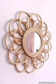 a mirror that is on the wall with rope around it and a flower shaped frame