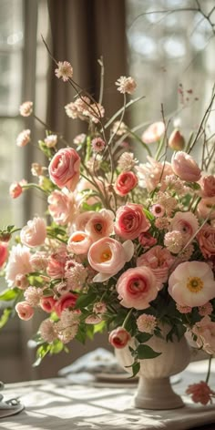 a vase filled with lots of pink flowers on top of a table next to a window