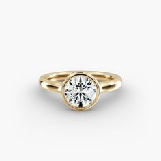 a yellow gold ring with a round cut diamond in the center, on a white background