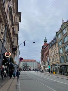 an empty city street with people walking on the side walk and buildings in the background