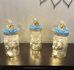 three mason jars with teddy bears in them on a wooden table next to a clock