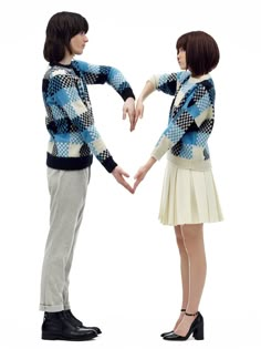 two people are holding hands and making a heart shape with their hands while standing next to each other