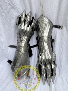 two metal armor gloves are laying on a white sheet