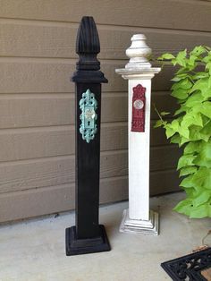 two black and white poles with clocks on them next to a planter in front of a house