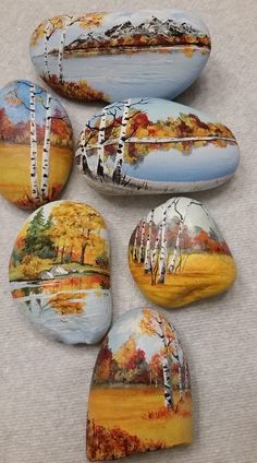 four painted rocks sitting on top of a white cloth covered floor next to each other