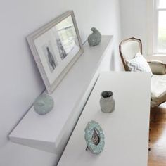 a white table with vases on it in front of a framed photo and chair