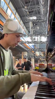 a man that is playing a piano in front of a sign with words on it