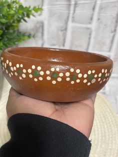 a hand holding a brown bowl with white dots on it