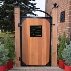 a wooden gate with a plaque on it in front of some potted plants and trees