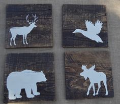 four wooden coasters with white moose and elk silhouettes on them, sitting on a table