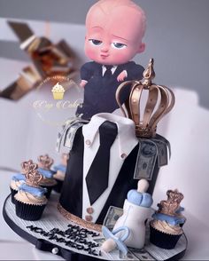 a cake made to look like a baby in a suit and tie with cupcakes