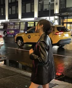 a woman is walking down the street in the rain