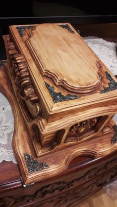 a wooden box sitting on top of a table next to a doily covered table