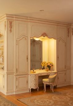 a white dressing table with flowers in vases on it and an armoire next to it