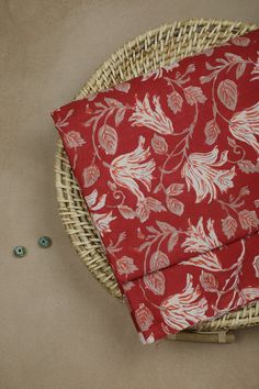 a wicker basket with a red and white flowered cloth on top of it