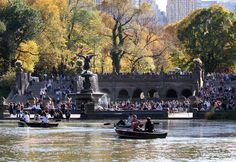 two boats with people in them are on the water near a fountain and some trees