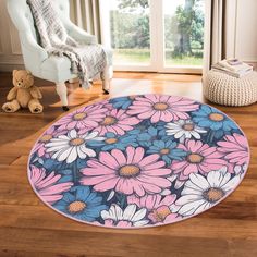 a blue and pink flower print rug on a wooden floor next to a teddy bear