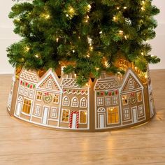 a small christmas tree in a tin with lights on it's sides and a gingerbread house under the top