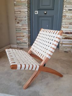 a wooden chair sitting in front of a door on the side of a building next to a brick wall