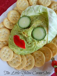 a plate with crackers, cucumber and cheese in the shape of a face