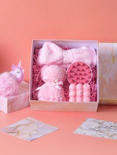 a pink box filled with lots of toys on top of a table next to a stuffed animal