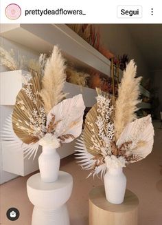 two white vases with dried flowers in them