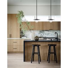 two stools in front of a kitchen island with marble counter tops and wooden cabinets