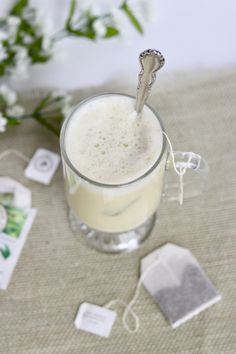 a glass filled with liquid sitting on top of a table next to a white flower