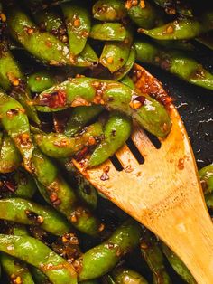 green peppers being cooked with a wooden spoon