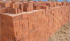 red bricks are stacked on top of each other in front of a building under construction