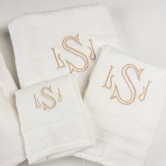 three white towels with gold embroidered monogrammed letters and the letter s on them