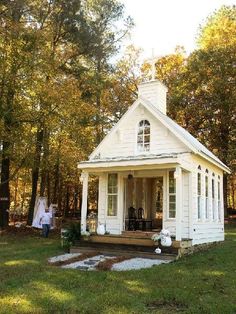 a small white house sitting in the middle of a forest