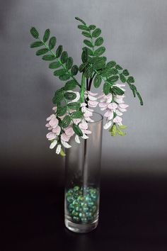 a vase filled with green and pink flowers on top of a black table next to a gray wall