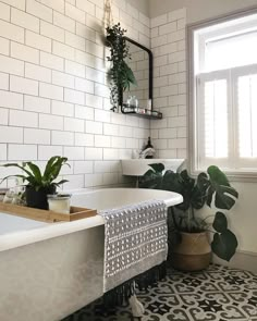 a bath tub sitting next to a window filled with green plants and potted plants