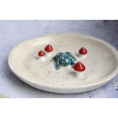 a ceramic plate with red and blue candies on it that looks like a frog