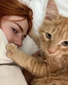 a woman laying in bed with a cat