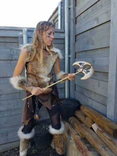 a woman dressed up as a viking holding a wooden stick and wearing an animal costume