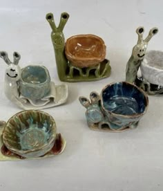 small ceramic animals sitting on top of a white table next to cups and saucers