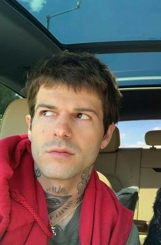 a man sitting in the back seat of a car with tattoos on his neck and chest