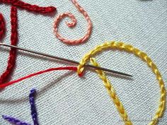 a close up of some scissors and thread on a piece of cloth with the word love written in it