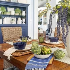 a wooden table topped with plates and bowls filled with succulents on top of it