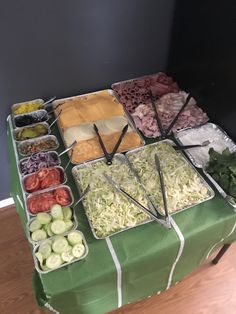 several trays of different types of food on a green tablecloth with white ribbons