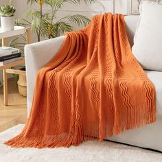 an orange blanket is draped over a white couch