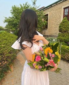 a woman holding a bouquet of flowers in her hands