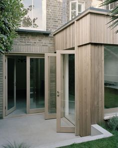 a wooden building sitting in the middle of a yard next to a lush green tree