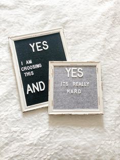 two signs that are on the side of a white wall and one is saying yes and it's really hard