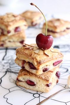 three desserts stacked on top of each other with cherries and almonds in the middle