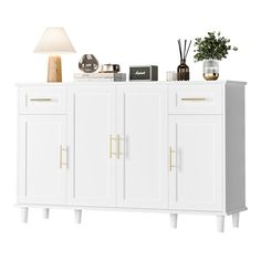 a white sideboard with gold handles and drawers next to a lamp on a table