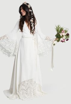 a woman in a white dress holding a bouquet of flowers and wearing a long veil