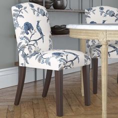 two chairs with blue and white floral upholstered backrests sit in front of a table